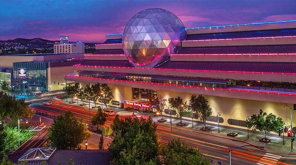 Exterior of the National Bowling Stadium a large building with lights outlining the top floors of the building and a large silver ball protruding from the roof